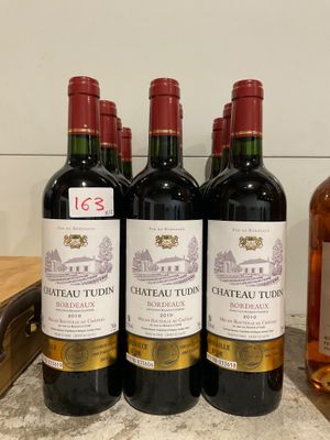 quatre bouteilles de vin sont alignées sur un comptoir, à côté d'une bouteille de vin