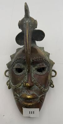 an antique bronze mask with a bird on top of it