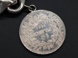 a silver coin on a chain on a black surface