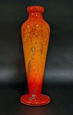 a red and orange vase sitting on a black surface