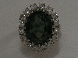 gros plan d'une bague avec une pierre verte entourée de diamants blancs