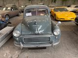 a old car in a parking lot with other cars in the background