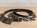 two leather bracelets with metal fringes on a wooden surface