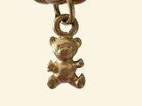 a gold chain with a teddy bear charm on it