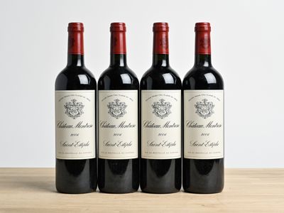 three bottles of red wine are lined up on a wooden table