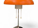 une lampe de table orange avec un pied en métal sur fond blanc