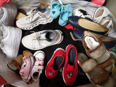 de nombreuses paires de chaussures posées dans un panier posé par terre