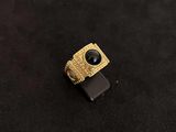 a close up of a black and gold ring on a black surface