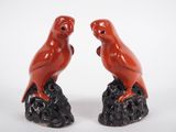 une paire d'oiseaux en céramique rouge posés sur un rocher, sur fond blanc