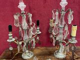 une paire de bougeoirs anciens en cristal posés sur une table en bois, sur fond rouge