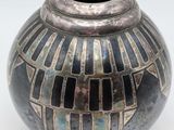 a black and silver vase sitting on a white surface