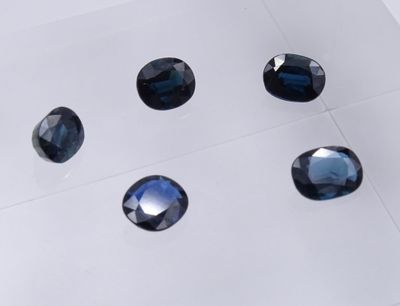 six saphirs bleus sont disposés sur un fond blanc