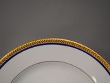 a white plate with a gold rim and blue trim