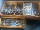 a lot of spoons and forks in a wooden box