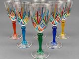 four wine glasses with colored stems are lined up on a gray surface