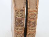 pair of old books sitting on top of each other on a white surface