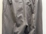 un pantalon gris à fines rayures blanches suspendu à un cintre devant un mur blanc