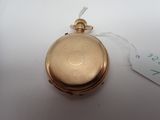 a gold pocket watch on a white table with a price tag