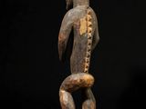 a wooden statue of a man holding a snake on a black background