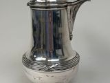 an antique silver coffee pot with a handle on a white surface