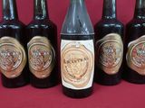 six bottles of beer are lined up in a row on a red surface