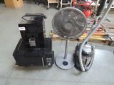 un ventilateur posé à côté d'une petite machine dans un entrepôt