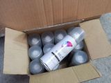 a cardboard box filled with cans of paint on the ground