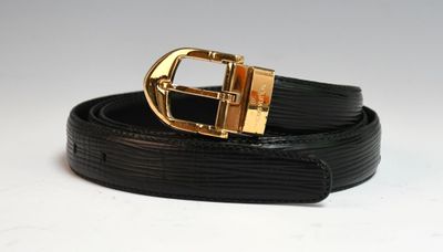 Gros plan sur une ceinture noire avec une boucle dorée