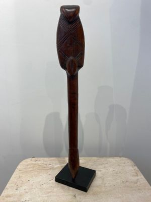 sculpture of a wooden owl on a stand on a marble surface