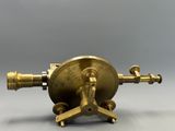 un gros plan d'une horloge en laiton posée sur un socle, sur une surface grise