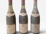 trois bouteilles de vin posées les unes à côté des autres sur une surface blanche
