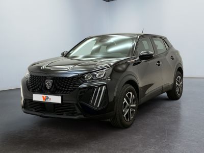 Une voiture noire est garée dans une pièce aux murs blancs.