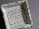 a small white box with writing on it in someone ' s hand