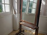 un miroir posé sur un pied dans une pièce dotée d'une fenêtre