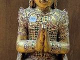 une statue représentant une personne assise sur une table en bois