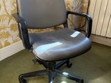une chaise de bureau grise posée devant un radiateur