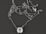 une chaîne en argent ornée d'un pendentif en diamant, posée sur un fond noir