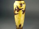 a yellow vase with birds on it sitting on a table