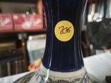 a blue vase with a yellow sticker on it sitting on a table