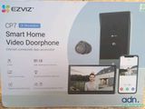 une image représentant une boîte sur laquelle figure une personne utilisant un téléphone portable et un interphone vidéo