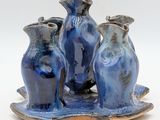 three blue vases sitting on a tray on a white surface