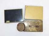 three pieces of metal and a wooden box on a white surface