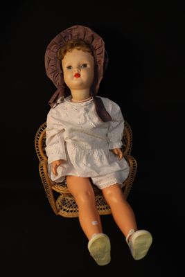 a doll that is sitting in a chair with a hat on