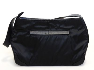 le sac noir est posé sur une surface blanche et est muni d'une bandoulière noire