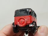 a hand holding a red and black toy car