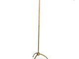 a brass floor lamp with a white shade on top of it