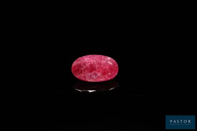 un rubis rose de forme ovale sur un fond noir