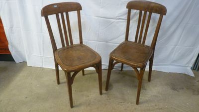 two wooden chairs sitting next to each other in front of a white backdrop