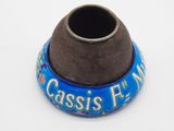 un petit vase bleu avec un socle marron posé sur une surface blanche