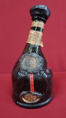 an old bottle of liquor sitting on top of a red table